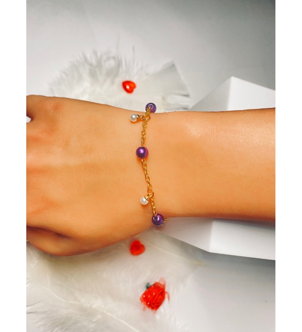 Bracelet doré avec perles violettes et breloque blanches