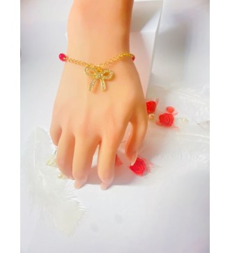 Bracelet doré avec perles rouges et pendentif nœud