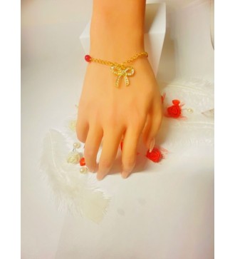Bracelet doré avec perles rouges et pendentif nœud