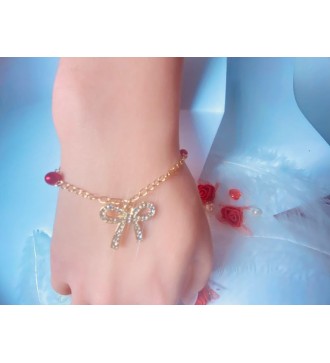 Bracelet doré avec perles rouges et pendentif nœud